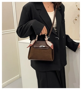 Detail of vintage matte brown leather Kelly bag with silk scarf on handle and metal lock