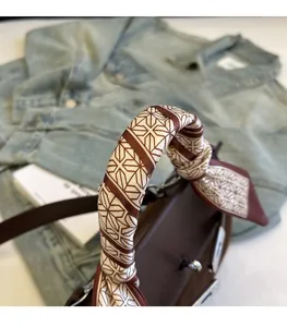 Close-up of retro brown handbag handle elegantly wrapped with geometric print silk scarf