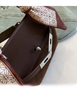 Detail of brown matte texture handbag with silver lock and silk scarf wrapped handle
