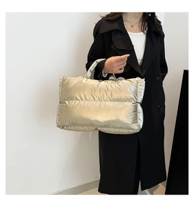 Side view of champagne gold quilted tote bag styled with a classic black wool coat