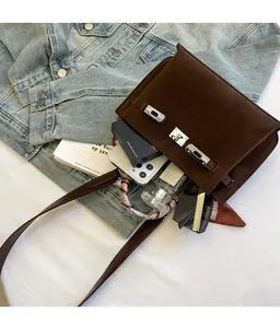 Flat lay of brown suede handbag with silver lock showing interior storage space