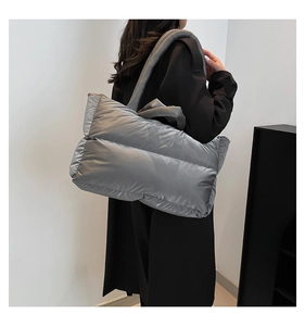 Close-up of a large grey quilted tote bag with metallic finish and wide shoulder strap