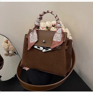 Detail of vintage matte brown leather handbag with floral silk scarf wrapped on handle