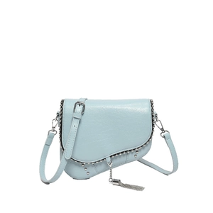 Détail du sac selle bleu clair avec clous argentés et glands métalliques sur cuir grainé