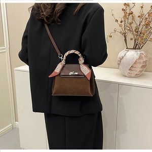 Brown suede satchel bag with printed scarf detail shown in a minimalist home setting