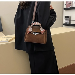 Close-up of brown matte suede bag featuring silk scarf detail and metal buckle