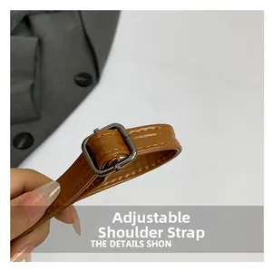 Detail showing the adjustable brown PU leather shoulder strap with dark metal buckle