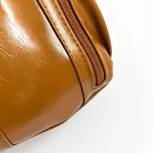Close-up of brown oiled leather bag showing texture, fine stitching and zipper detail