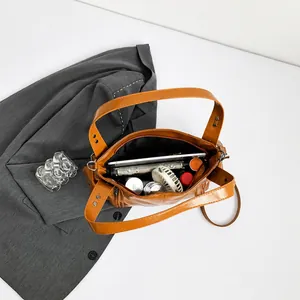 Spacious interior of a brown PU leather bag showing daily items and wide storage capacity