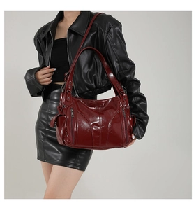 Detail of dark red glossy PU tote bag with multiple zippers and adjustable shoulder strap