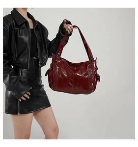 Detailed view of deep red oil wax leather tote bag with side zippers on model