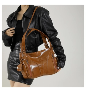 Detail of a brown oil wax leather tote bag with multiple pockets and adjustable shoulder strap