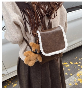 Detail of vintage brown mini backpack featuring white faux fur trim and a cute bear charm
