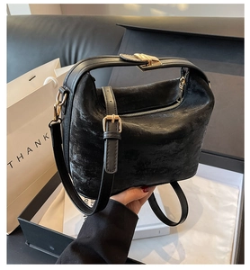 Détail d'un sac à main noir vintage mat avec boucles dorées dans une boîte cadeau