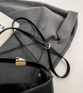 Détail de la bandoulière réglable en cuir noir avec boucle en métal doré et texture lisse