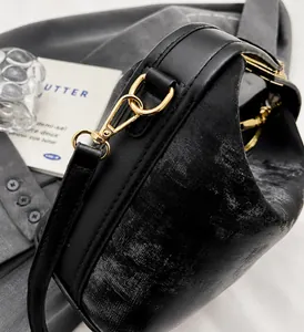 Détails d'un sac en cuir noir texturé scintillant avec ferrures métalliques dorées