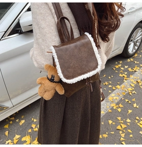 Close-up of brown vintage backpack with faux shearling trim and cute teddy bear charm
