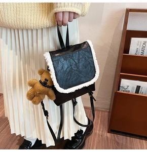 Detail of black PU leather backpack with faux fur trim and cute plush bear charm