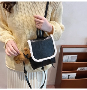 Detail of mini black PU backpack with white faux fur trim and cute bear charm