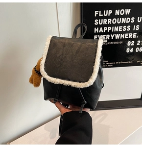 Detail of black PU leather backpack featuring white faux fur trim and bear pendant
