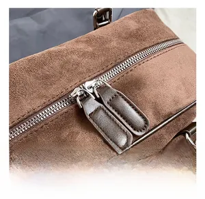 Macro shot of dual metal zippers on a dark brown suede bag with precise stitching detail