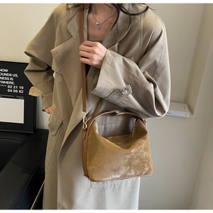 Détail d'un sac en daim marron vintage avec fermoir métallique et poignée supérieure