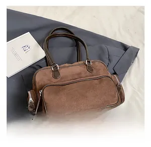 Detail view of brown suede shoulder bag with multiple zippered pockets and leather handles