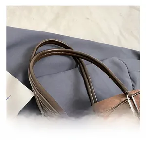 Detail of dark brown faux suede shoulder bag featuring a durable leather handle and silver metal hardware
