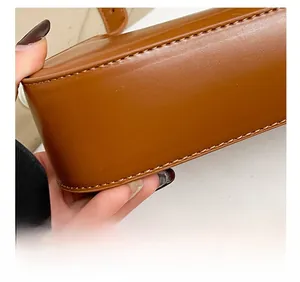 Close-up of precise stitching on the bottom corner of a premium brown leather handbag