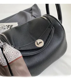 Detail of black lychee grain leather bag with silver hardware and decorative silk scarf