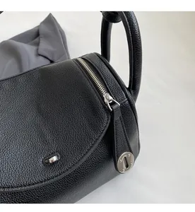Close-up of smooth silver zipper and lychee pattern leather texture on black shoulder bag