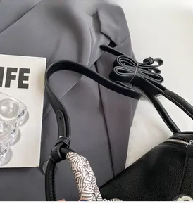 Close-up of black lychee grain leather handbag with decorative silk scarf on handle