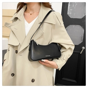 Fashionable black leather underarm saddle bag with white print carried by a model