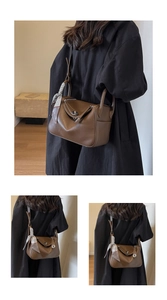 Detail of brown litchi leather texture and silk scarf handle on stylish boston bag