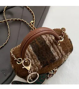 Détail d'un mini sac seau en peluche marron avec anse en cuir et chaîne dorée
