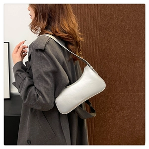 Close-up of a silver minimalist baguette bag featuring a thin shoulder strap and sleek texture