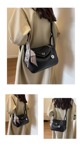 Detail of black pebbled leather handbag with gold clasp and elegant silk scarf handle