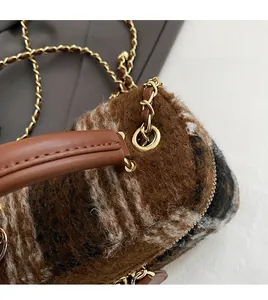 Détail du fermoir doré et de la texture en laine à carreaux d'un petit sac bandoulière