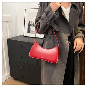 Detail of red faux leather shoulder bag with FASHION & BAG print worn with a grey coat