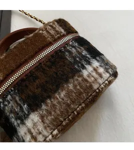 Détail du tissu en laine à carreaux et zip doré sur ce mini sac boîte en peluche