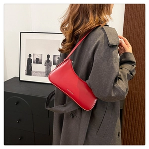 Model wearing a bright red leather hobo bag with a minimalist shoulder strap design