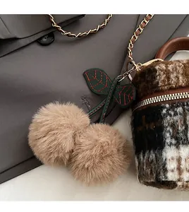 Détail du charm cerise en fourrure avec feuille brodée sur un sac à main en tweed chic
