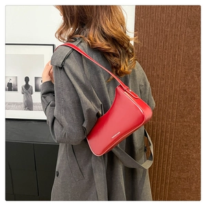 Detail of red glossy leather shoulder bag with Fashion & Bag text and sleek strap