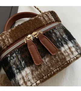 Détail d'un mini sac seau à carreaux avec double fermeture éclair dorée et anse en cuir