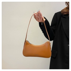 Detail of caramel brown faux leather shoulder bag with silver zipper and printed text