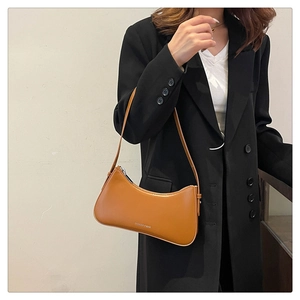 Asian model wearing a minimalist brown faux leather underarm saddle bag for summer fashion