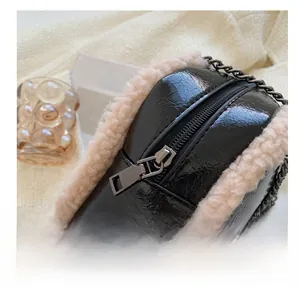 Detail view of the smooth zipper and beige plush trim on the black leather handbag