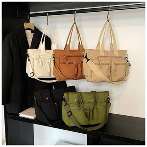Detailed view of large multi-pocket tote bags displayed in beige, black, and brown colors