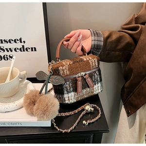 Detail van bruin geruite tweed mini box tas met kersen bont pompon en een kettingriem