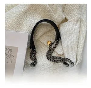 Macro view of metal chain strap with black leather padding on a lamb wool crossbody bag